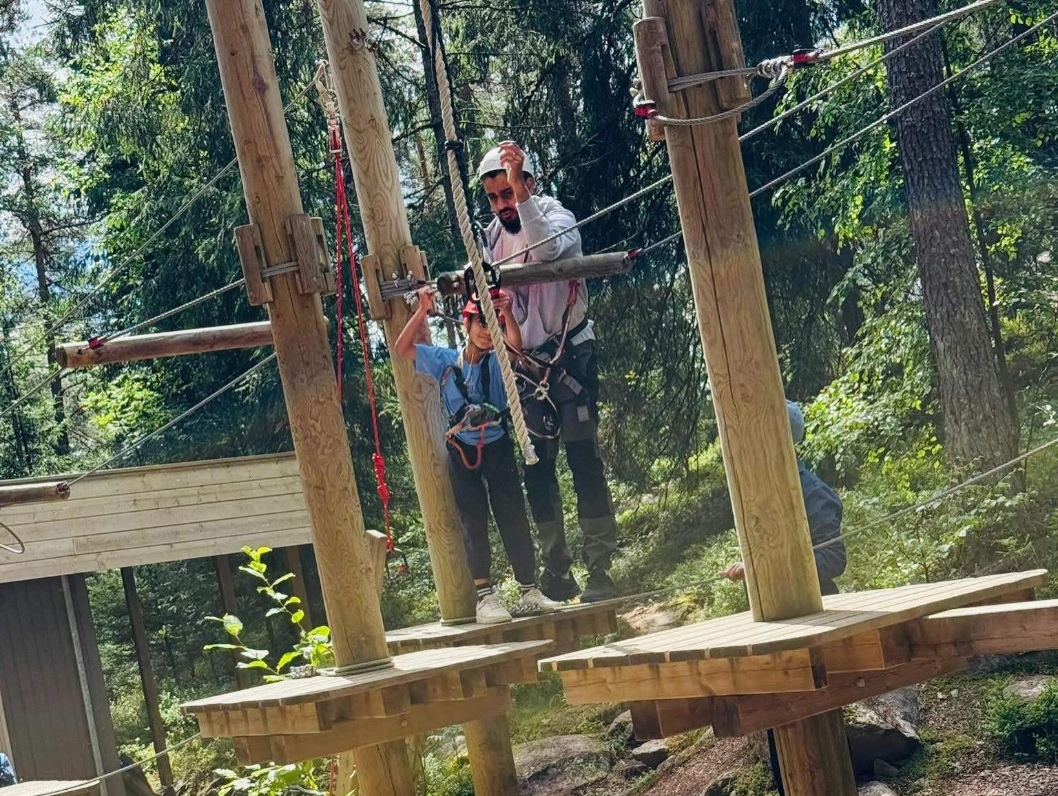 En voksen hjelper en gutt med sikkerhetsutstyret